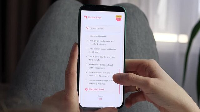Person scrolls a mobile chicken curry recipe with step-by-step cooking instructions and nutrition facts, highlighting digital meal planning, home cooking and healthy food choices.