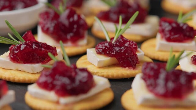 Party appetizers with brie cheese, cranberry sauce and fresh rosemary on crackers