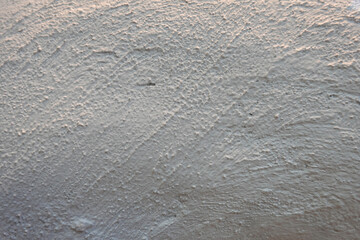 Surface d'enduit mural à grain rugueux avec une lumière rasante © luzulee