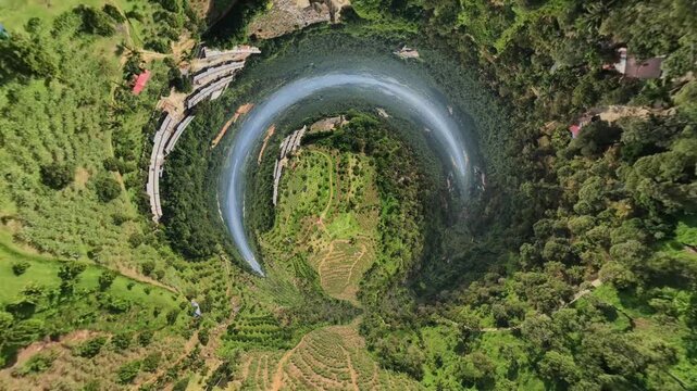 An aerial shot captures a distinctive circular artificial lake nestled among lush green forests and terraced land, showcasing a peaceful natural landscape.