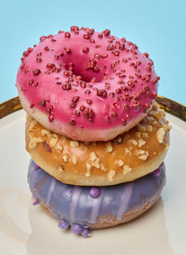 Stack of three multicolored donuts with glaze and sprinkles