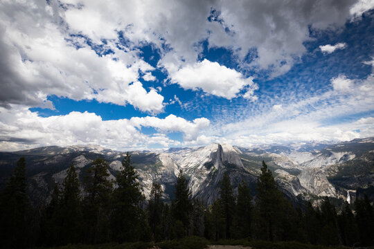 Panoramic view of Half Dome and Sierra Nevada mountains under cloudy sky in Yosemite