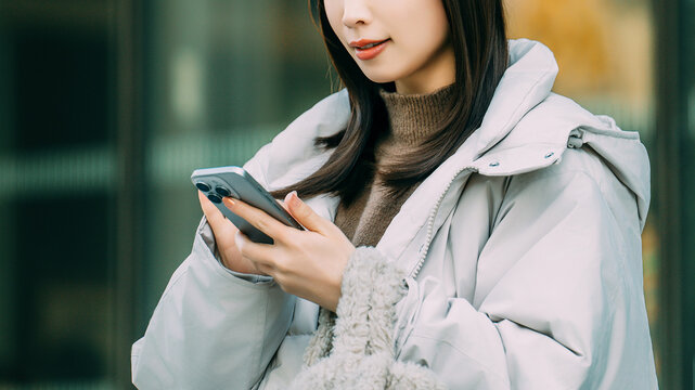 冬の街角でスマートフォンを使う笑顔の女性