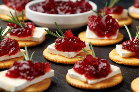 Party appetizers with brie cheese, cranberry sauce and fresh rosemary on crackers