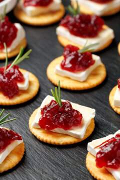 Party appetizers with brie cheese, cranberry sauce and fresh rosemary on crackers