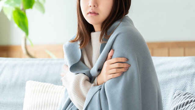 寒気がしてブランケットを羽織る女性