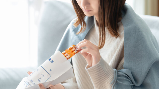 薬を飲む体調不良の女性