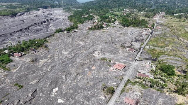 Aerial drone view of abandoned village buried in gray lava and ash after Mount Semeru eruption.