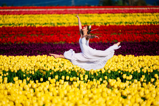 Ballet white dancer leaping above vibrant tulip fields