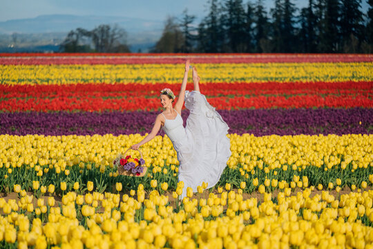 Ballet dancer posing in white dress in colorful tulip field