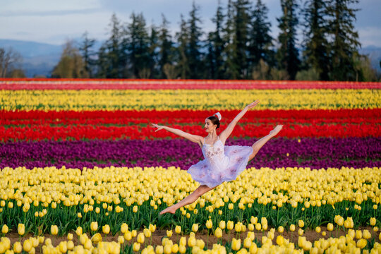 Ballet white dancer leaping in colorful tulip field