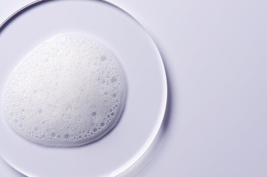 A sample of a cosmetic cleansing product in the form of foam. On a glass circle.