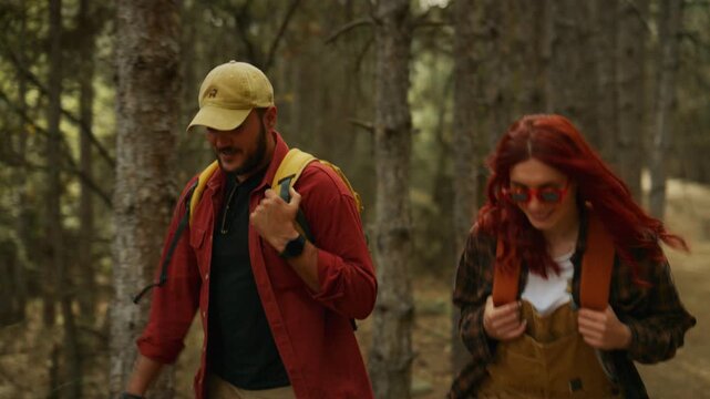 Man hikes with a couple through a pine forest on a dirt trail, walking with backpacks during an outdoor adventure.