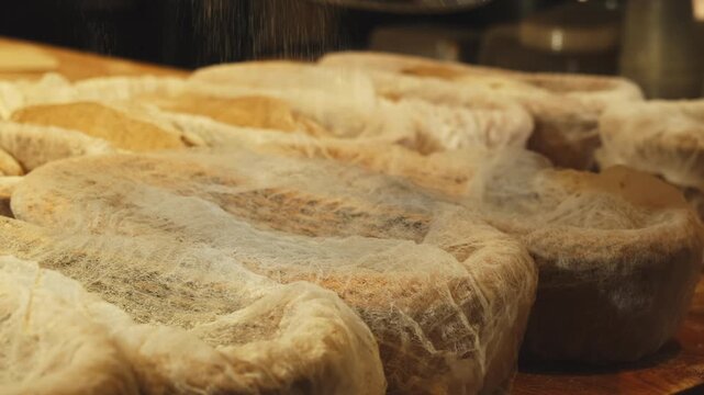 Pouring flour into proofing baskets covered with gauze sheets on table closeup. Breadmaking technique to bake soft pastry in bakery shop