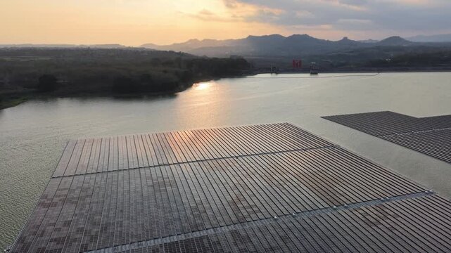 Expansive floating solar array reflecting golden sunset over Karangkates reservoir with distant hills and dam.