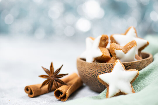 Christmas holiday sweets, homemade cinnamon stars with hazelnuts and almonds, cookies and biscuits with icing glaze, bokeh light 