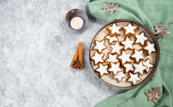 Christmas holiday sweets, homemade cinnamon stars with hazelnuts and almonds, cookies and biscuits with icing glaze, candle light 