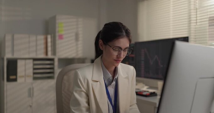 Woman financial analyst working at stock trading terminal with candlestick charts in office