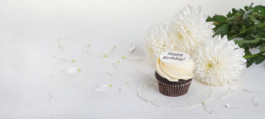 Cupcake decorated with the inscription Happy birthday! with a bouquet of peonies. Holiday greetings concept, banner, background. Festive still life with selective focus and copy space for text © Nymphalyda