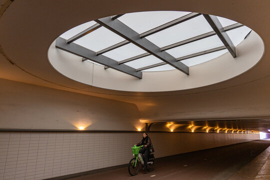 Rotterdam, South Holland, Netherlands - 27 March 2026: View of a cyclist in the underground tunnel at Rotterdam Central Station, under a large circular skylight with modern lighting.