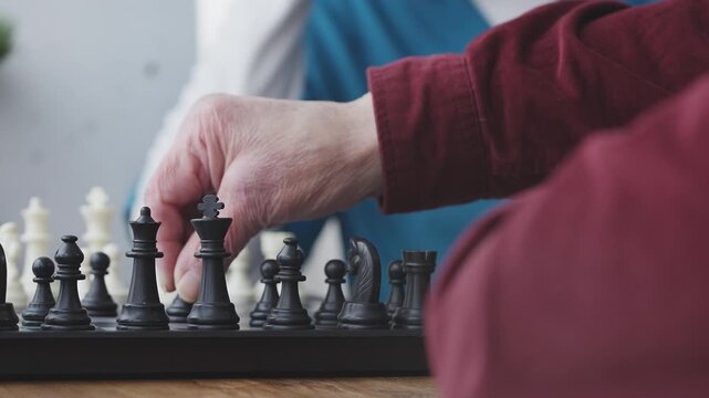 Close-up of senior man and nurse playing chess, improving cognitive skills