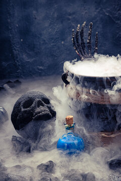 Close-up of smoking cauldron with black skull and blue potion