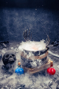 Steaming witch cauldron with skeleton hands, potions, and black skull
