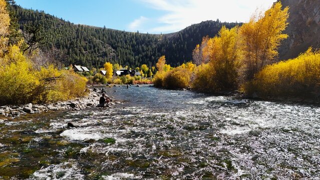 Gunnison, Colorado, United States - 04 October 2026: View of Gunnison River with fly fishermen, golden autumn foliage, and mountain peaks in the background.