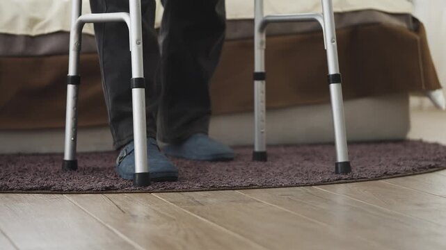 Close-up of senior man with chronic condition moving with walker at home