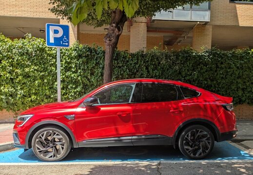 Vista lateral de un autom&oacute;vil Renault Arkana Esprit
Alpine de color rojo, en un aparcamiento con accesibilidad para personas con movilidad reducida. Madrid, Espa&ntilde;a, 11 de julio de 2026