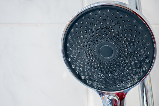 Dirty shower head covered with limescale and hard water deposits.
