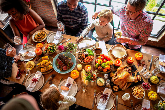 Diverse group enjoying a festive meal around a table with various dishes.