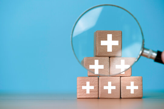 Value added and customer benefits concept with magnifying glass and plus signs for symbol of business profit growth , health insurance , benefit and economy development concept