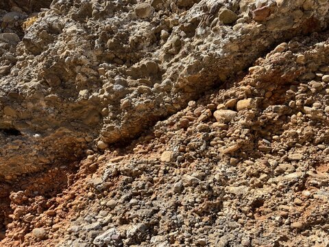 Close-up texture of natural conglomerate rock layer composed of cemented pebbles and gravel stones in an outdoor geological terrain in Aspendos, Antalya, Turkey.