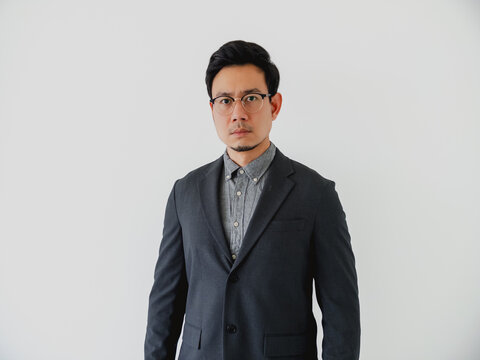 Professional Asian businessman in a dark suit and glasses standing against a clean white background.
