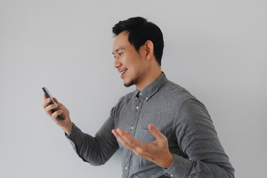 Happy Asian man smiling and gesturing while using smartphone for video call or social media.
