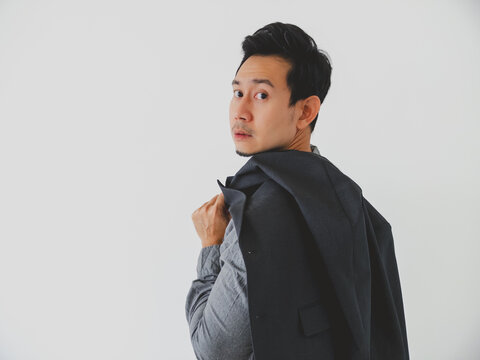 Young Asian man in smart casual attire, blazer draped, looking over shoulder.