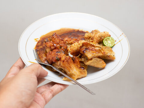 Indonesian traditional food from West Java region called Batagor stands for baso tahu goreng, a fried fish cake with tofu in peanut butter sweet-hot sauce served in a white plate