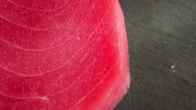 Close-up of fresh raw tuna showing its rich red color and delicate muscle fibers. Fresh seafood texture and raw fish ingredient for Japanese cuisine. High quality 4k footage