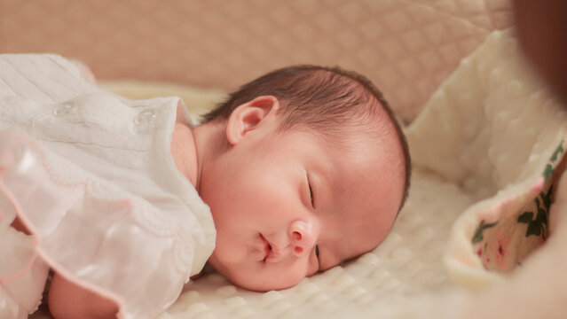 Close up newborn baby, infant, sleeping peacefully on a soft white blanket, quiet moment of rest, comfort, and early infant development.