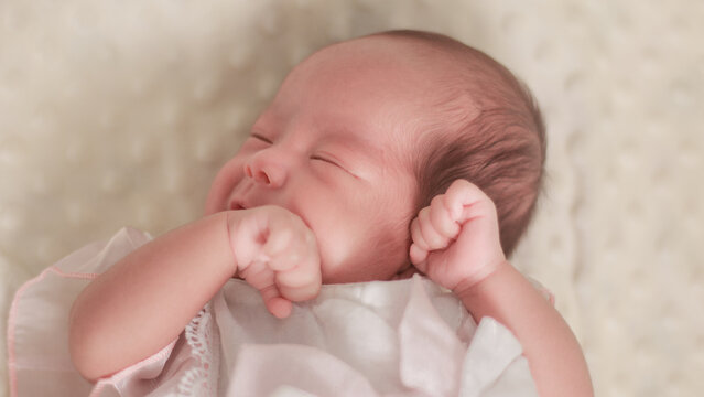 Close up newborn baby, infant, sleeping peacefully on a soft white blanket, quiet moment of rest, comfort, and early infant development.