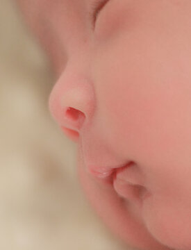 Close up newborn baby, infant, sleeping peacefully on a soft white blanket, quiet moment of rest, comfort, and early infant development.