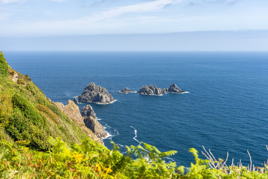 Rocky islets off steep green cliffs in deep blue Atlantic, Galicia, Spain