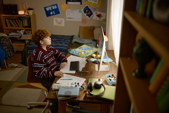 Caucasian teenager studying online at computer with remote tutor during distance education. Useful for e-learning platforms, tutoring services, digital schooling ads