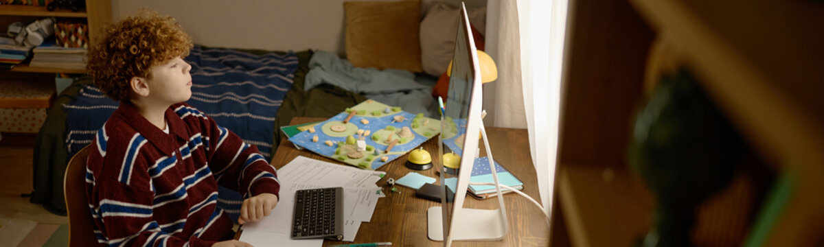 Caucasian teenage boy studying online with computer at home. Visual representing distance education, tutoring services, e-learning platforms, and remote academic development
