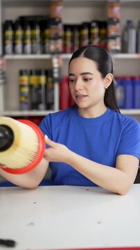 Female auto mechanic presenting car engine air filter in workshop