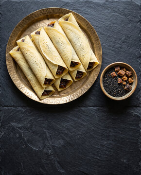 Assamese til pitha rice rolls with black sesame and jaggery for Magh Bihu, top view with copy space, vertical