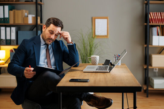 Stressed businessman reviewing paperwork in office