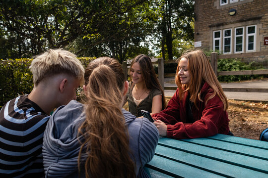 Friends catch up over a phone in a shaded courtyard