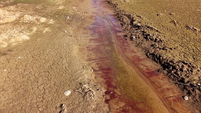 Aerial view follows a dried up river channel across the exposed bed of a dried up lake in France